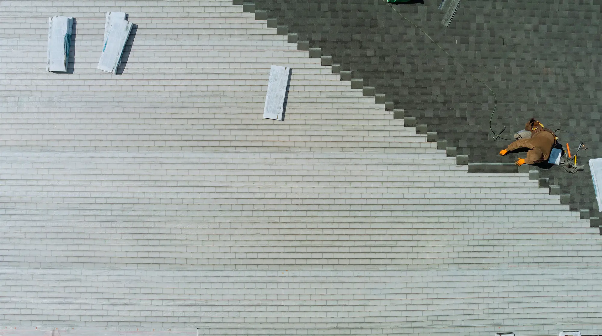 Roofing installer fastening new shingles during a full roof replacement