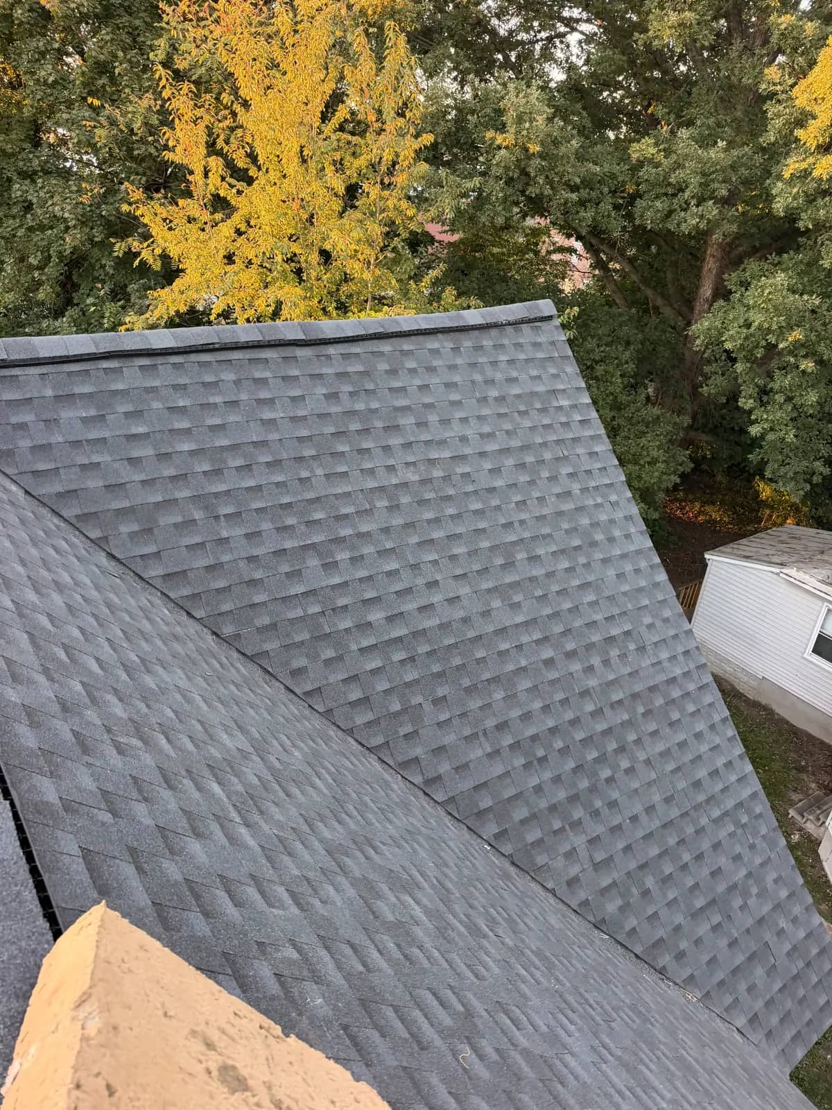New Charcoal shingles across connected Salem roof slopes with a ridge vent and trees behind