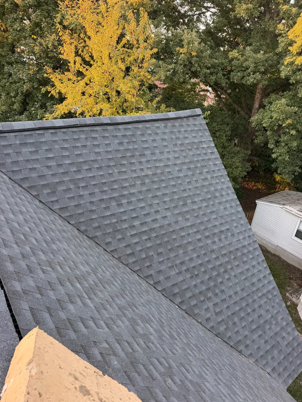 New Charcoal shingles across connected Salem roof slopes with a ridge vent and trees behind