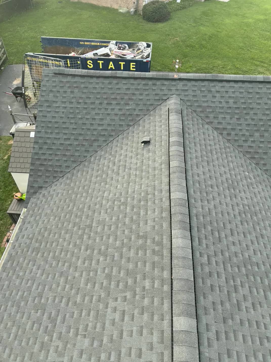 Completed shingle ridge leading toward an intersecting roof section in Southampton