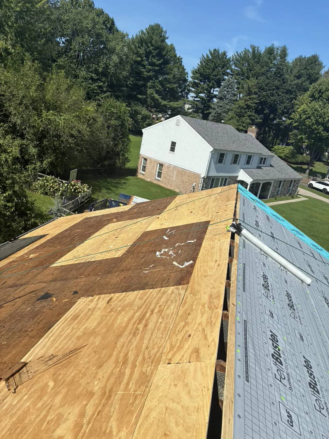 Exposed wood roof decking beside an underlayment-covered slope in Southampton